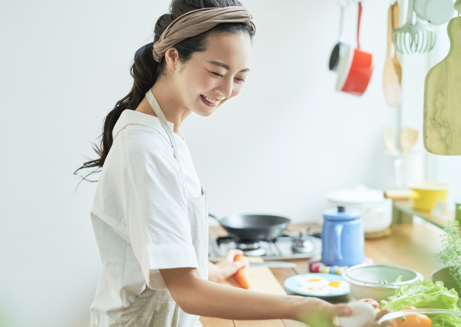 女性がスマートスピーカーと料理をしている写真